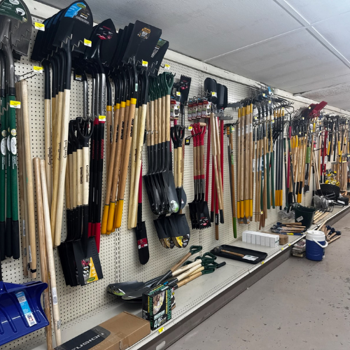 Shelves filled with various garden tools, including shovels, rakes, and hoes, organized neatly by type and size. The display conveys a tidy and orderly atmosphere.