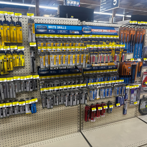 A well-organized hardware store display features various drill bits in vibrant packaging labeled with types, such as brite, black oxide, and cobalt drills.