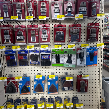 Display of various power tool accessories in a hardware store, neatly arranged on a pegboard with yellow price tags. The setting is organized and industrial.
