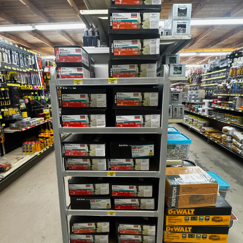 Shelves stacked with various power tool accessories in a hardware store aisle. Bright lighting and organized layout create a utilitarian atmosphere.