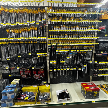 A store display of neatly arranged wrenches and tools on shelves, with various sizes and packaging. The setting is bright and organized, conveying a practical tone.